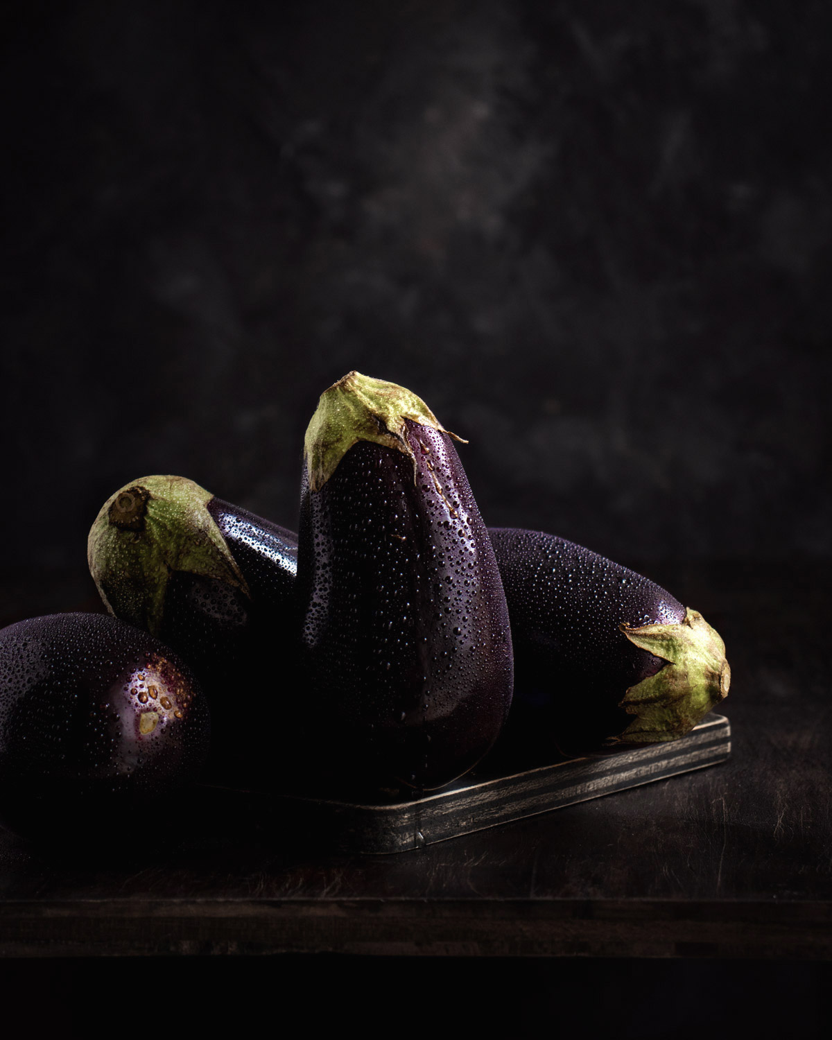 fotografía de berenjenas en fondo oscuro, estilo dark and moody