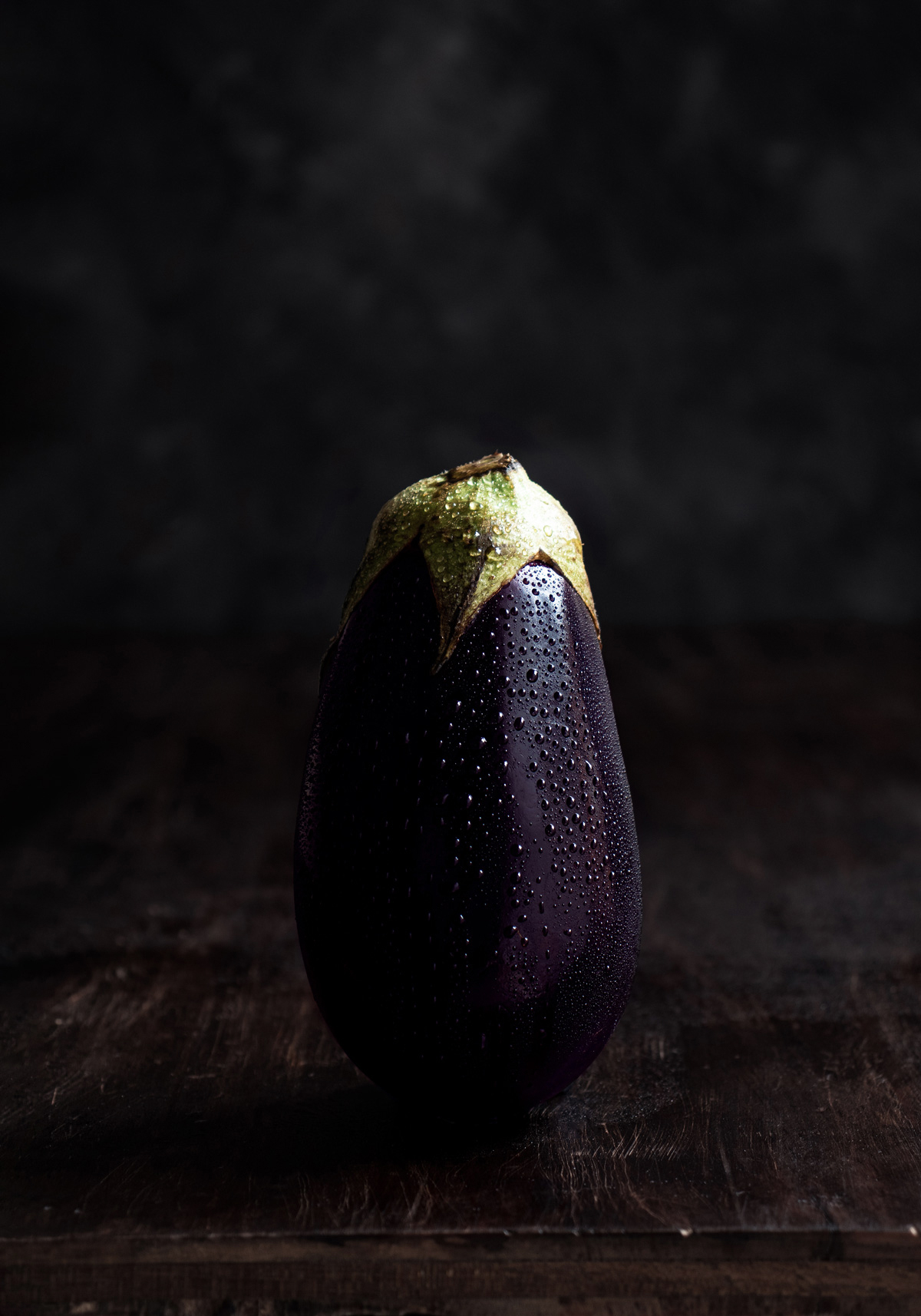fotografía de una berenjena en fondo oscuro, estilo dark and moody