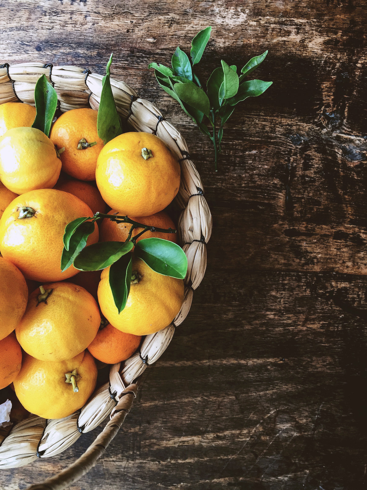 Fotografía de naranjas miniaturas en canasta, estilo dark and moody - Kumquats