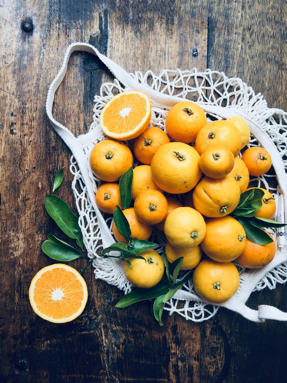 Fotografía de naranjas miniaturas en bolsa tejida, estilo dark and moody - Kumquats