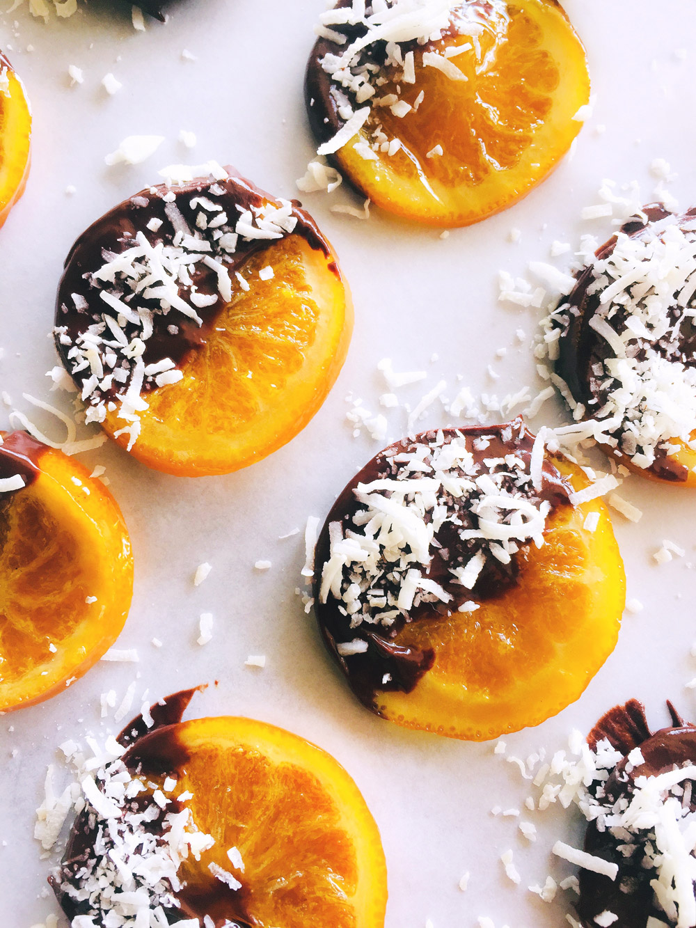 Fotografía de rodajas de naranjas miniaturas confitadas, recubiertas con chocolate y coco