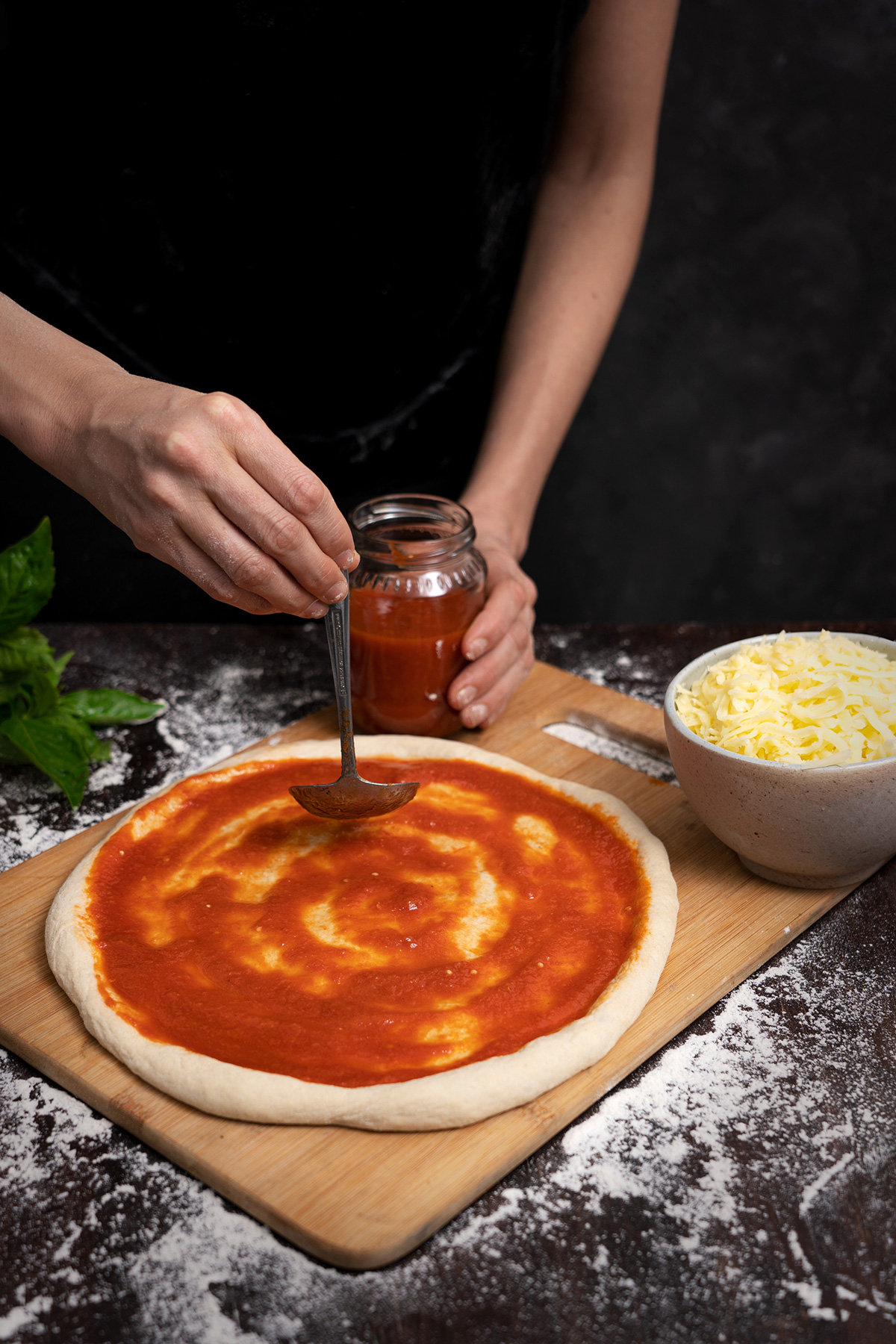 Fotografía de proceso de elaboración de pizza napolitana, untar salsa de tomate