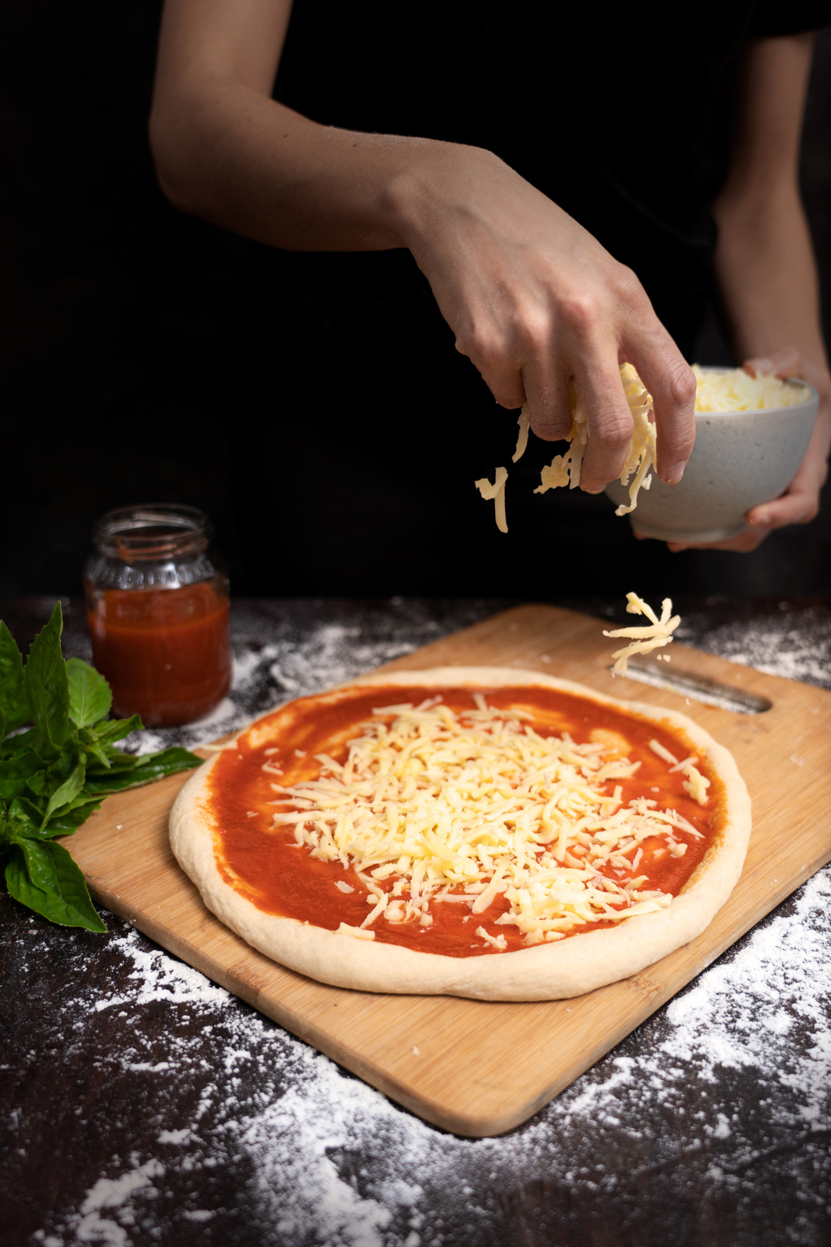 Fotografía de proceso de elaboración de pizza napolitana, esparcir queso rallado