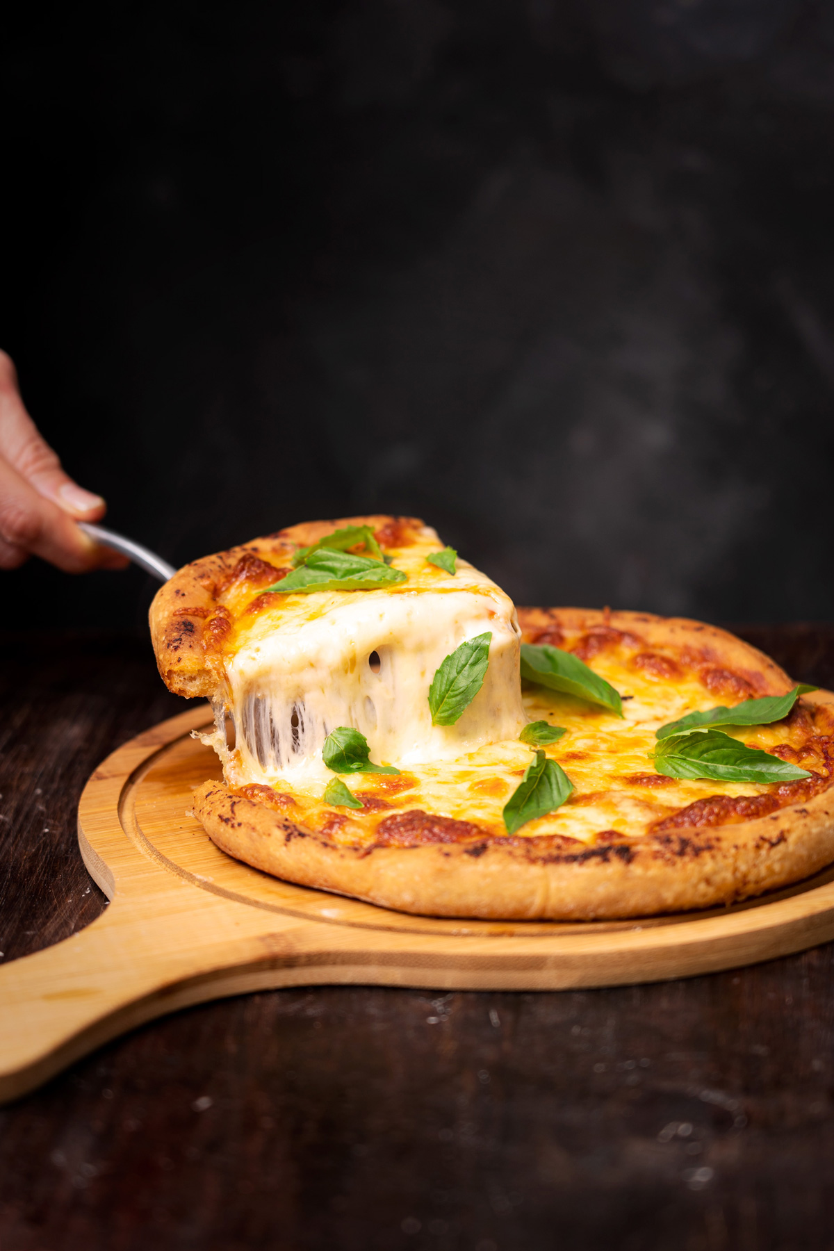 Fotografía de queso estirándose al sacar una tajada de pizza napolitana