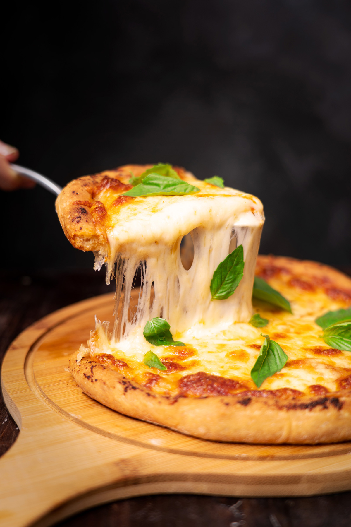 Fotografía de queso estirándose al sacar una tajada de pizza napolitana