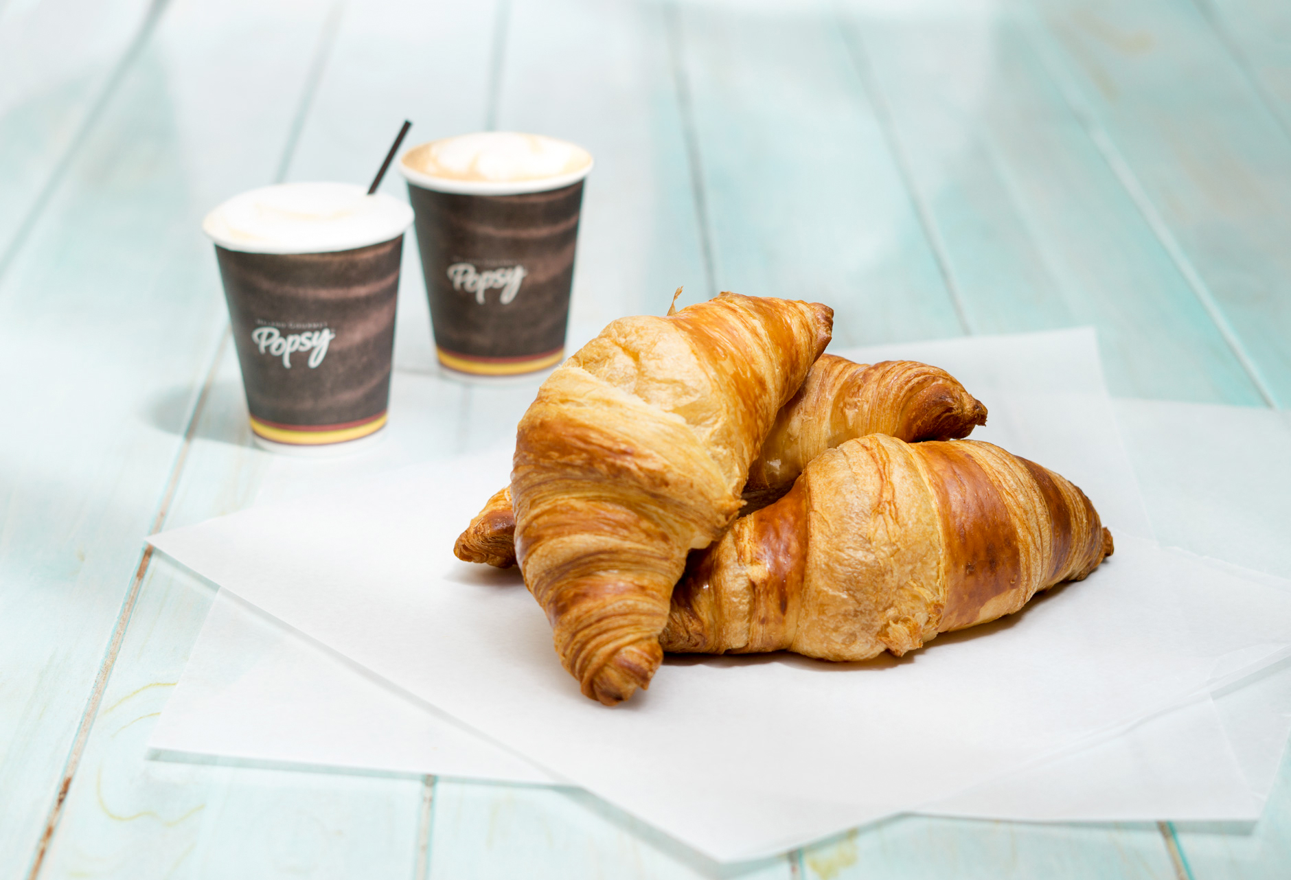 Fotografía de croissant y dos vasos de café al fondo